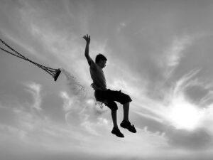 A boy jumping off a swing into a body of water