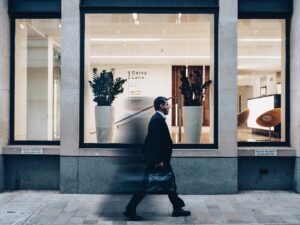 A man carrying a briefcase and walking in front of a building